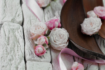 
Pink roses on gray bricks background with satin ribbon and brown bark.