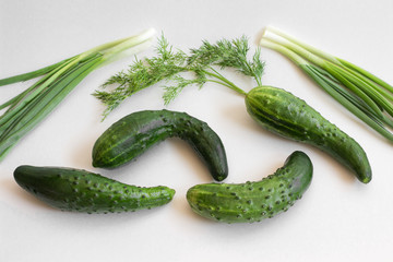 Fresh cucumbers with green onions and dill on a white background