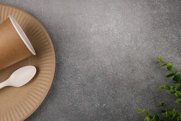 A set of eco-friendly utensils with green leaves on a concrete background. The concept of eco-friendly utensils. Flatlay. Copy space. From above.
