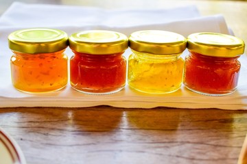 pineapple, orange and strawberry jams in the small glass bottle