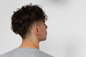 Cool, young hipster guy with short curly hair is posing in studio on isolated background. Style,...