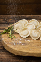 Frozen dumplings with meat on a wooden plate on a wooden background