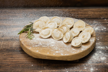 Frozen dumplings with meat on a wooden plate on a wooden background