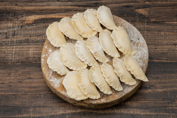 Frozen dumplings on a wooden plate on a wooden background