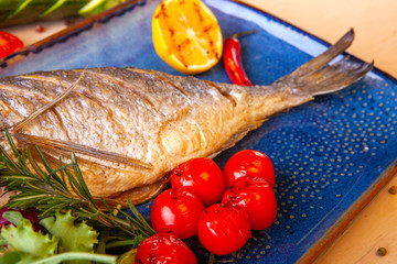 cooked fried fish on a plate with vegetables