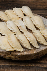 Frozen dumplings on a wooden plate on a wooden background