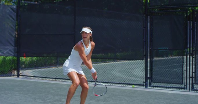 Girl hitting tennis ball in match
