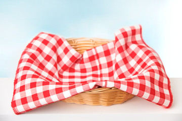 
Wicker basket with a red checkered cloth inside on a white tablenapkin