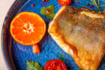 cooked fried fish on a plate with vegetables