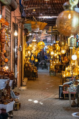 Fototapeta na wymiar Marrakech, Morocco - 12.27.2019: Lightful and vivid streets of the Medina of Marrakech with local handmade manufacturing shops selling lamps and metalic items