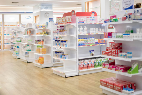 Medicines arranged in shelves, Pharmacy drugstore retail Interior blur abstract background with medicine healthcare product on glass cabinet with neon light.