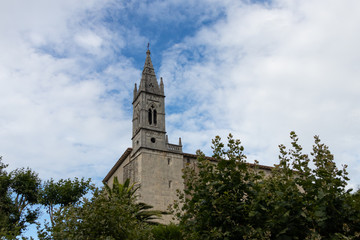 Fototapeta na wymiar campanario de una iglesia con nubes alrededor y arboles