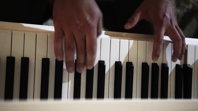 Man plays the piano in a dark room, white and black keys