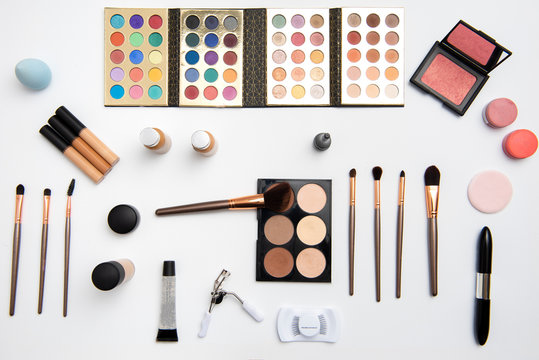 Kit de maquillaje que incluye paleta de sombras, aplicadores o brochas, rubores, pesta&ntilde;as , rimel, enchinador y bases acomodados sobre un fondo blanco
