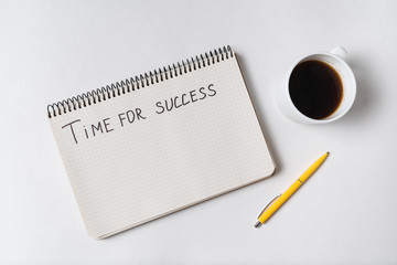 Motivational inscription TIME TO SUCCESS. Top view of notebook, pen and cup of coffee. White background