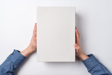 Children's hands holds white cardboard box on white background. Top view. Shipping concept.