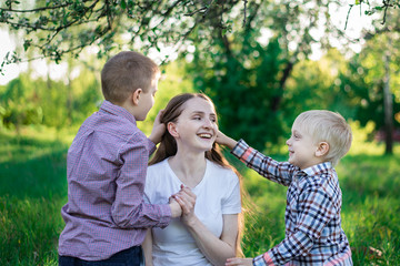 Young beautiful mother playing with his two sons. Children stroking mom's head. Love and care