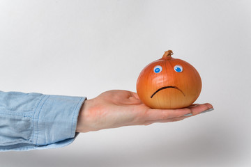 Funny onion lies on hand. Napiform onion with Googly eyes and smile. White background.