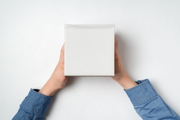 White box in children's hands on white background. Top view. Copy space.