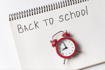 Notepad with the words BACK TO SCHOOL and vintage alarm clock.