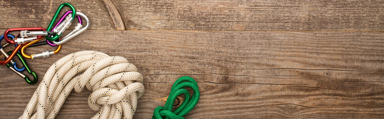 panoramic shot of hiking ropes and carabiners on wooden surface