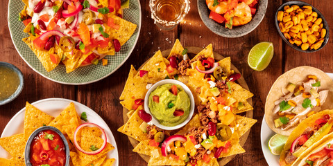 Mexican food panorama, shot from above on a rustic wooden background. Nachos, guacamole, tequila, tacos, a flat lay