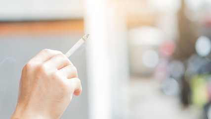 A man who is smoking with a blurred background hand