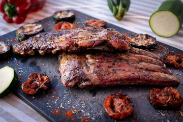 Barbecued pork ribs an vegetables. They're on a blackboard.