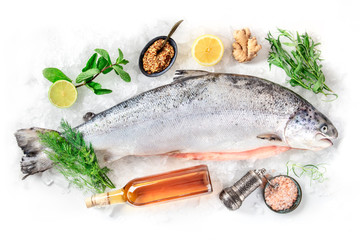 Fresh salmon, shot from above on a white background with various condiments and wine