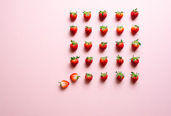 Strawberries aligned on a pink table.