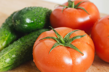 Fresh tomatoes and cucmbers on the wooden table with white background