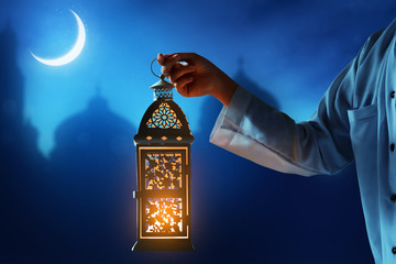 Muslim man holding arabic lantern, Ramadan kareem background