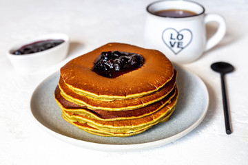 Breakfast with pancakes, jam, nuts and black coffee, close-up