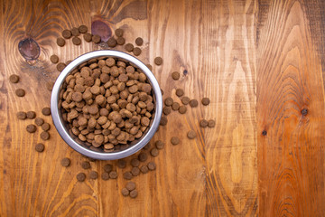 Dog food in bowl on wooden table. Loose dog food. From above. Copy space