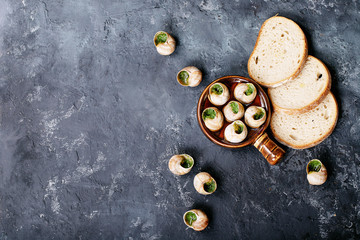 Baked snails with garlic butter and fresh herbs in a frying pan, selective focus