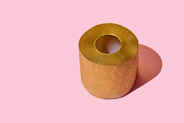 Creative still life with golden toilet paper, hot commodity during covid-19 and period of self isolation. Pink background, copy space