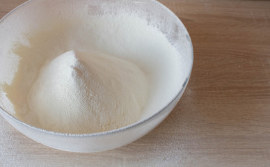 sifted white flour in a clear glass bowl on a wooden table. the concept of baking