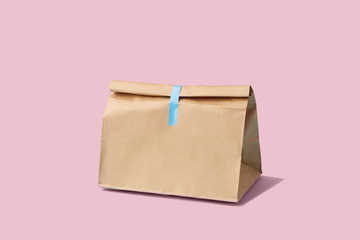 Brown clear empty blank paper bag for food delivery on pink background with copy space. Packaging template mock up fast food.