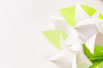 Close up three white Origami paper tulips with green leaves on white background. Abstract backdrop. Copy space. DIY concept.