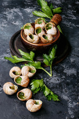 Baked snails with garlic butter and fresh herbs in a frying pan, selective focus