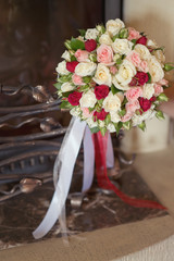wedding bouquet with multicolored ribbons lies by the fireplace