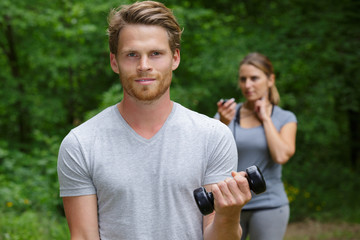 sporty man training with dumbbells in park