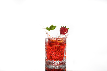 Red alcohol cocktail with splash, strawberry and mint leaf isolated on white.