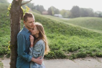 Naklejka premium Romantic and happy caucasian couple in casual clothes hugging on the background of beautiful blooming trees. Love, relationships, romance, happiness concept. Man and woman walking outdoors together.