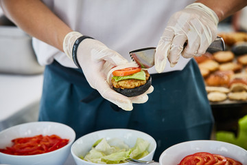 Preparing burger adding vegetable and sauce. cooking,