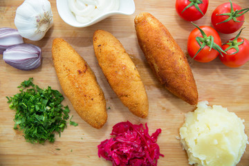 Ukrainian tradition food on a wooden board . Red cabbage sauerkraut in a small bowl . mashed potatoes . Mayonnaise, Garlic, Onion, Tomatoes. Chopped coriander.Chicken Kiev cutlets with parsley leaves.