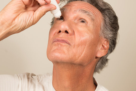 Senior Man Applying Eye Drops To His Eyes