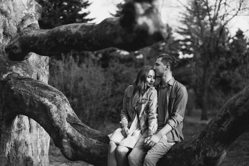 Romantic and happy caucasian couple in casual clothes hugging on the background of beautiful blooming trees. Love, relationships, romance, happiness concept. Man and woman walking outdoors together.