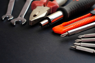 A Set of a lot of different red tools for working include hammer wrench bit pliers, screwdriver,  paper knife, screwdriver nozzle, key on black background 