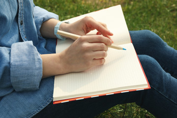 Girl draws outdoor sitting on green grass. Creativity concept